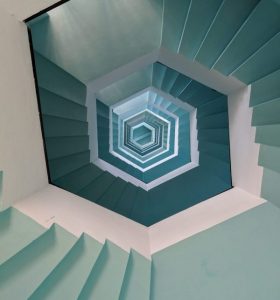 View from the top of a light cerulean and white, octagonal spiral staircase symbolizing the opioid fentanyl overdose crisis